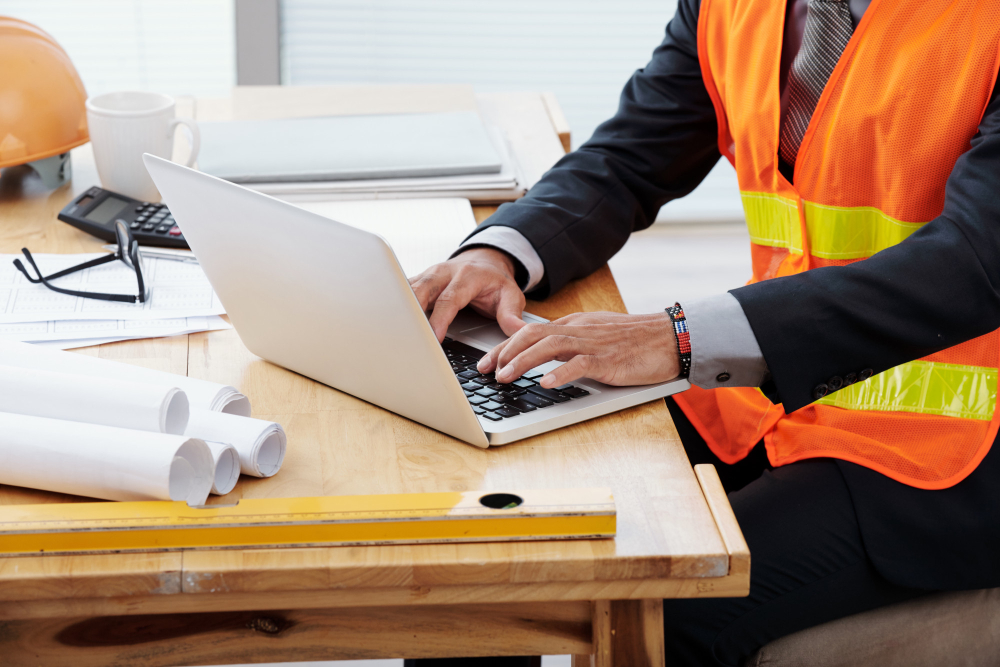 man-neon-safety-vest-business-suit-sitting-desk-using-laptop