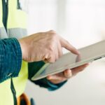Contractor reviewing pay application on a digital tablet at a construction site