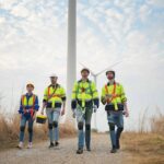 Wide perspective of wind turbine engineers walking down a concrete path