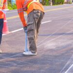 Road workers marking lines on a road to be painted over in white