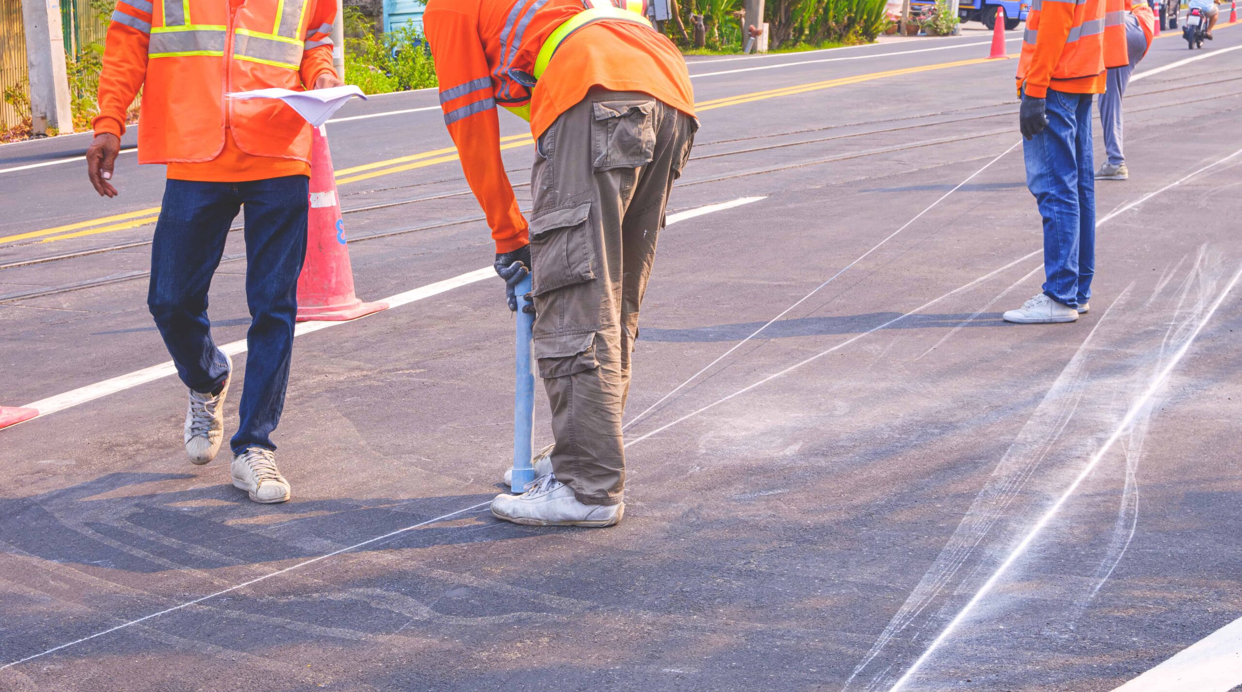Road workers marking lines on a road to be painted over in white