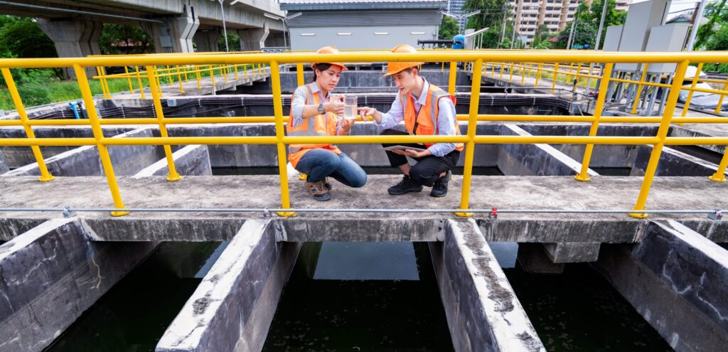engineers take water samples from wastewater treatment pond