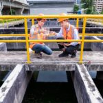 engineers take water samples from wastewater treatment pond