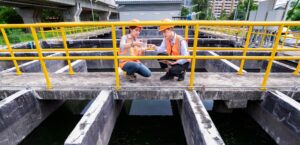 engineers take water samples from wastewater treatment pond
