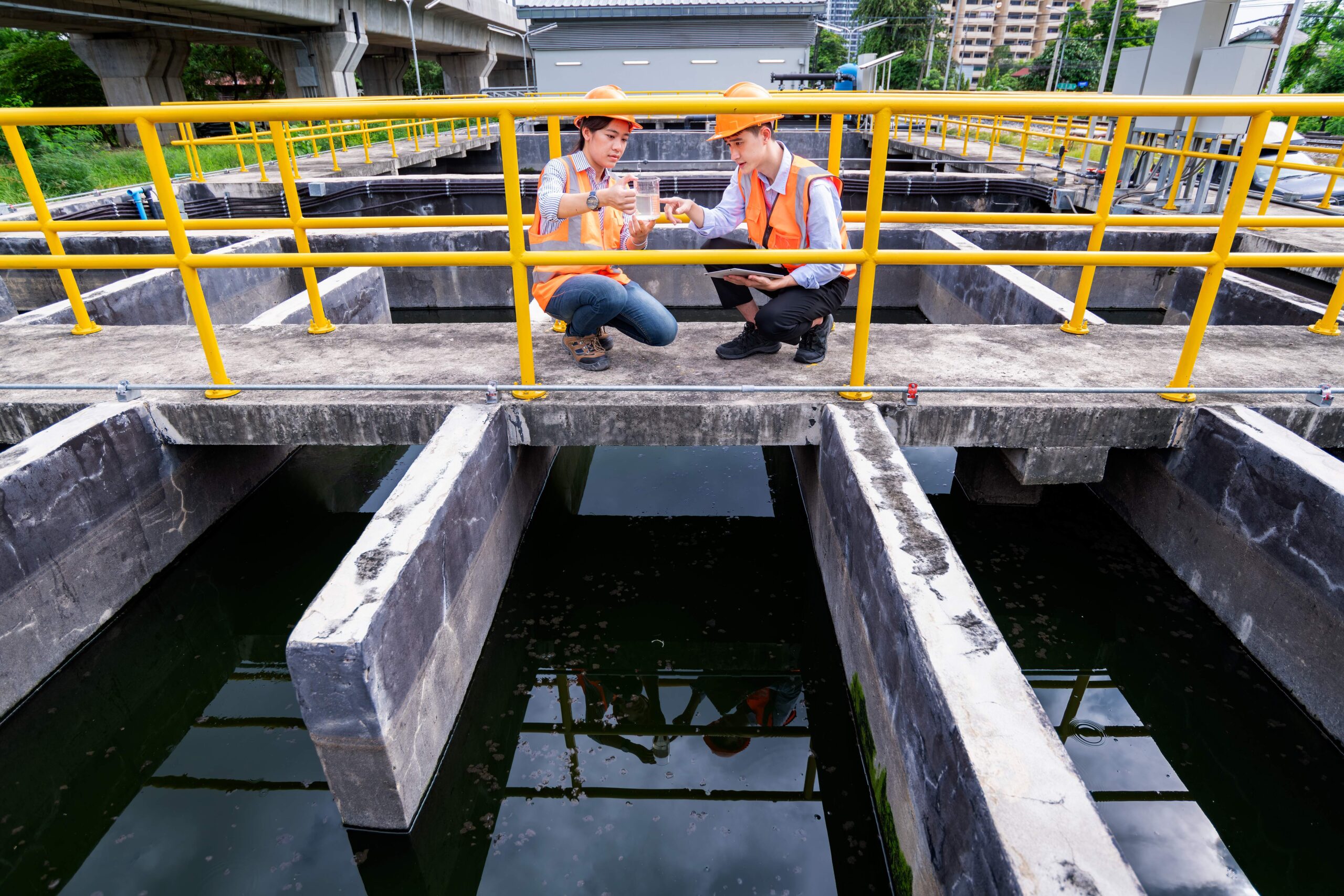 engineers take water samples from wastewater treatment pond